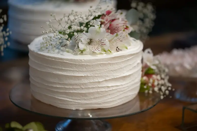 Hvit bryllupskake med riflet krem og friske blomster
