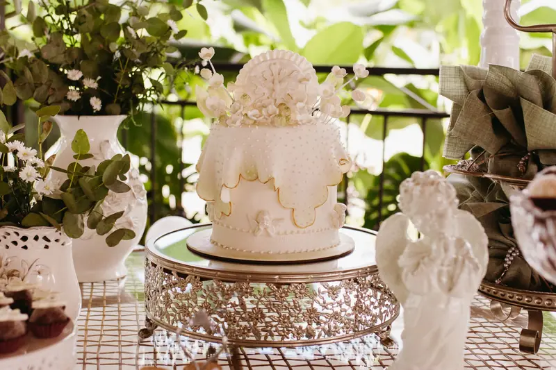 Hvit kake med blomsterpynt på kakefat i hage